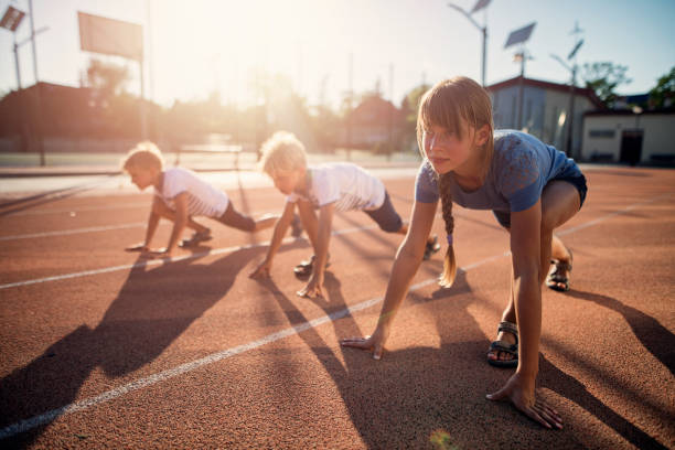 Kids preparing for track run race start. Kids are waiting for the signal for the race to begin. Hot and sunny summer day.